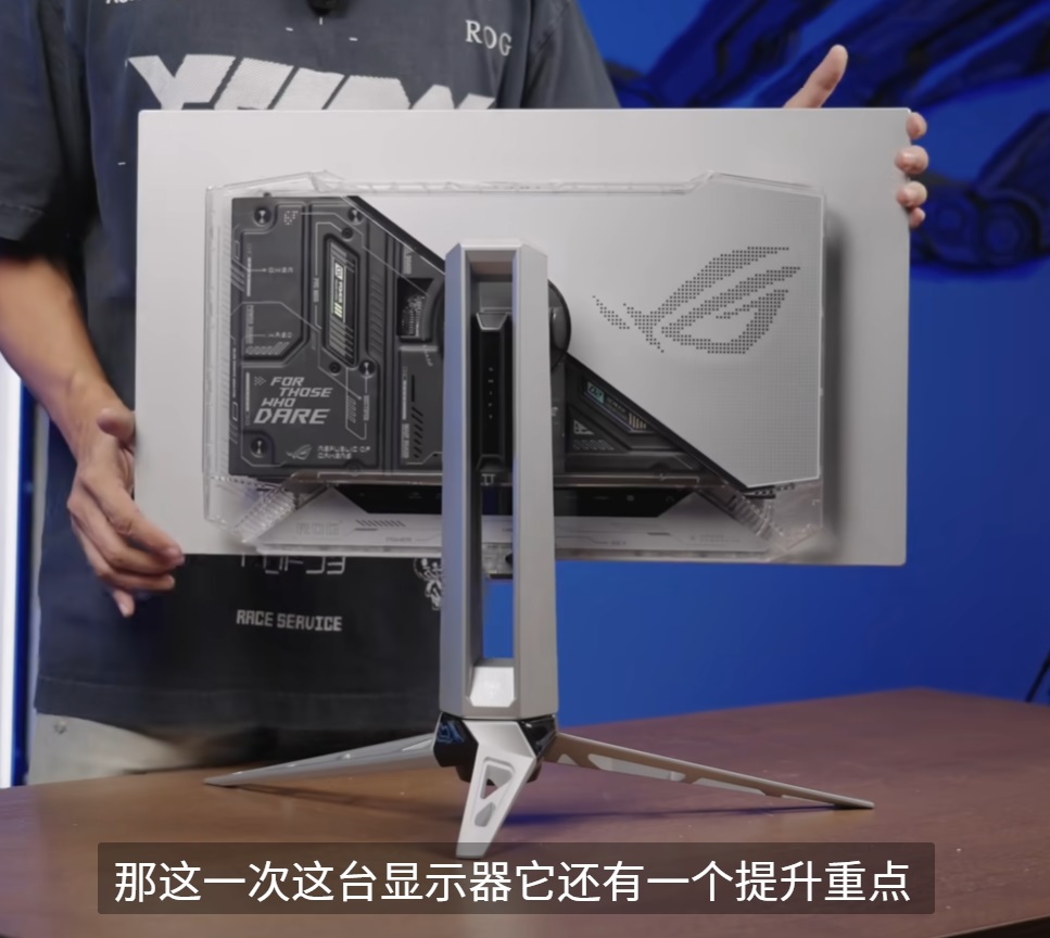 ASUS ROG monitor with “FOR THOSE WHO DARE” text on the back, placed on a wooden table.