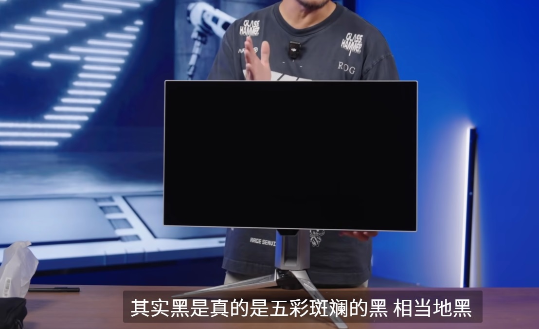 ASUS ROG monitor on a desk, person's t-shirt reads GLASS HAMMER.