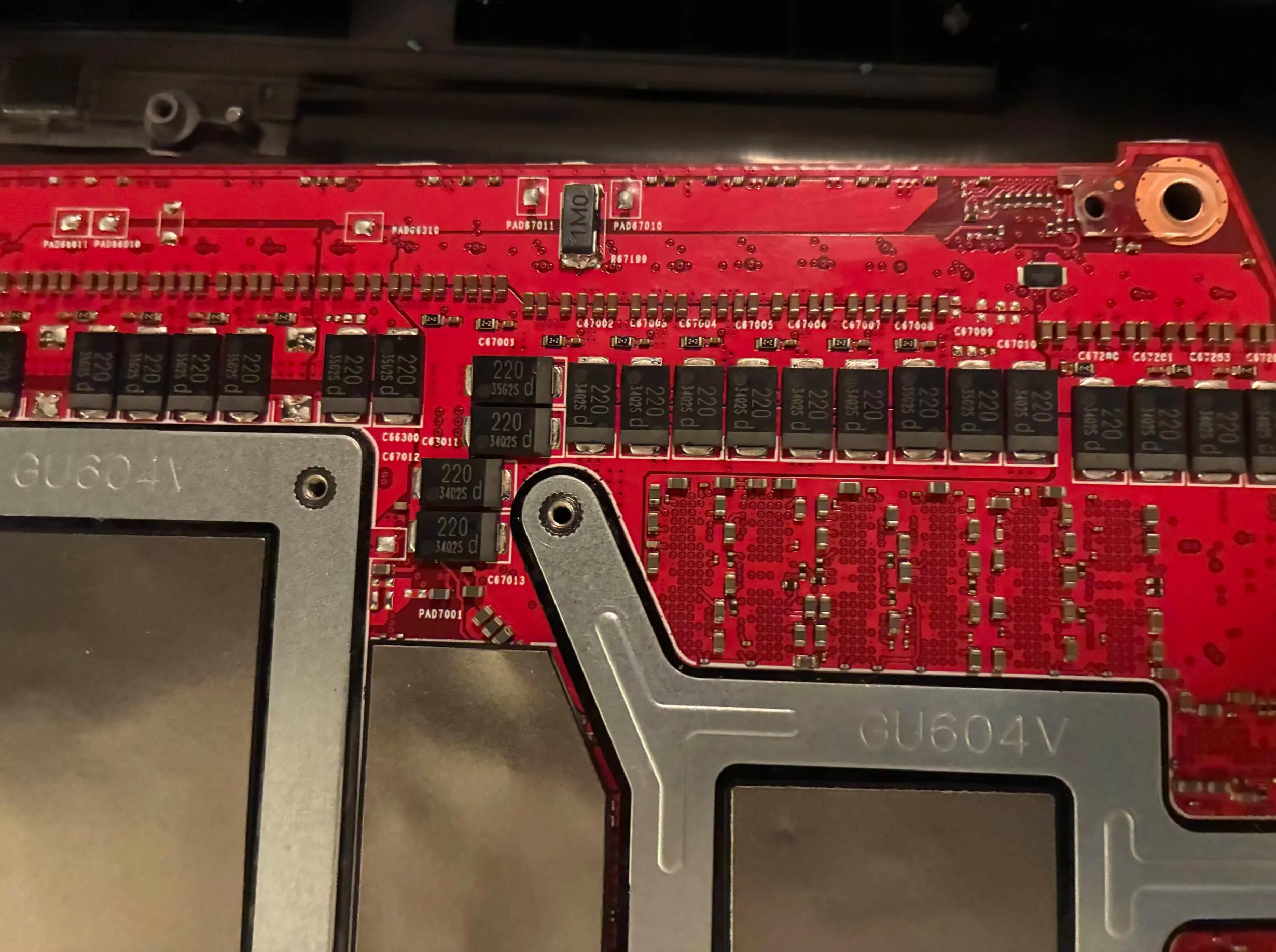 Red circuit board with text GU604V and numerous black components labeled 220 16V 330S d in a hardware setup.