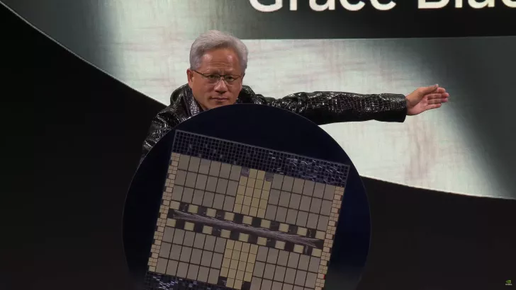 Person on stage holding a large NVIDIA chip with the text Grace on the screen behind.