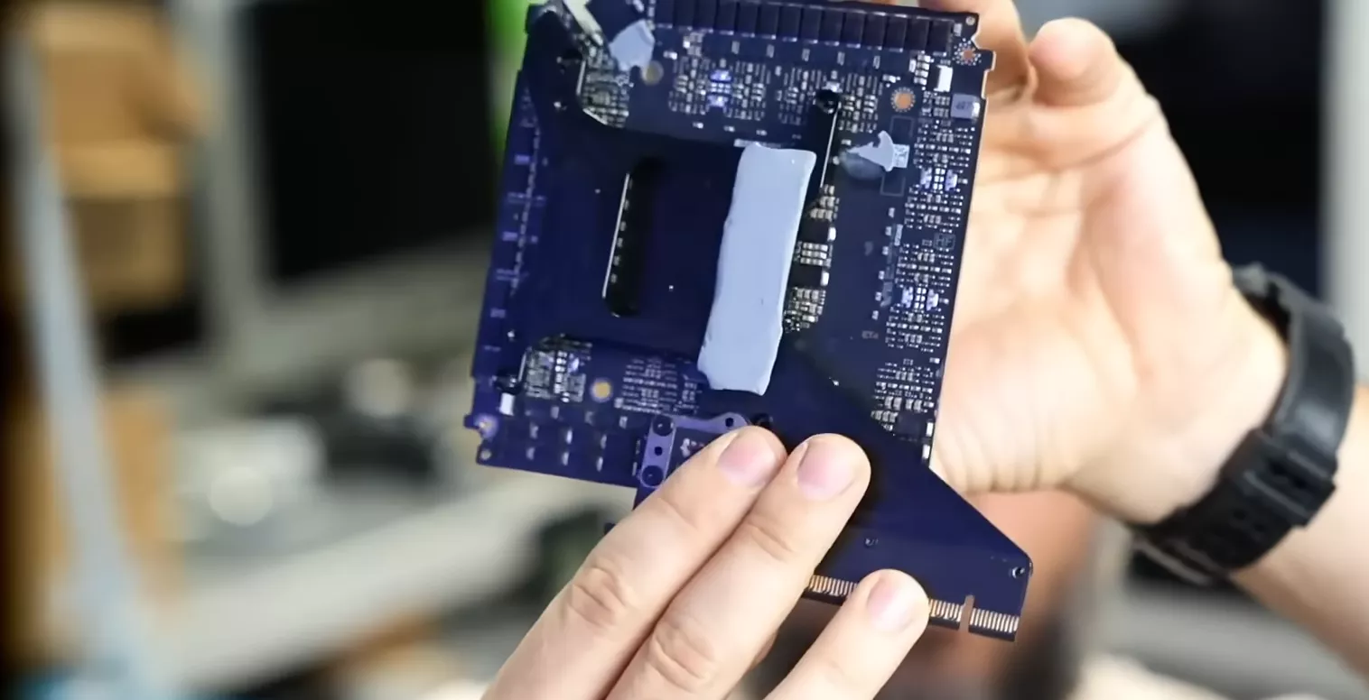 Unbranded circuit board held by a person in a tech workspace.