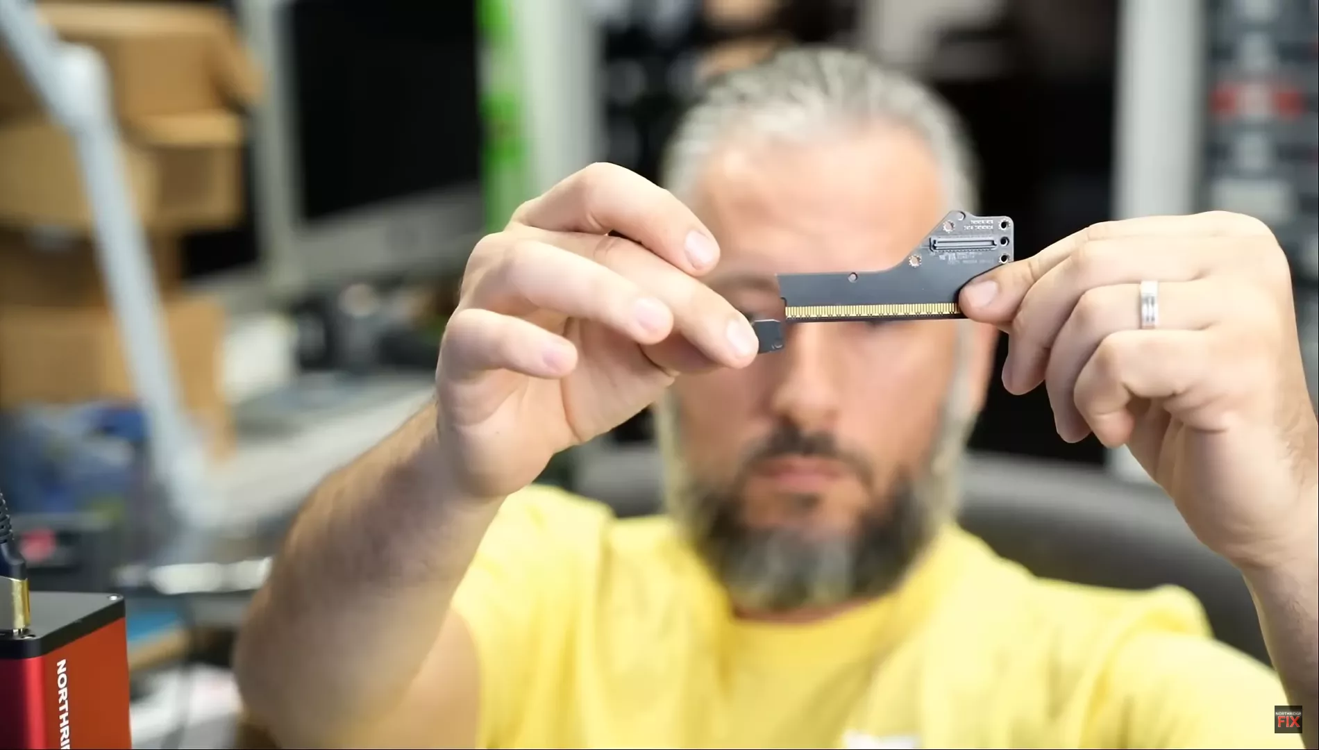 A person in a workshop examines a component labeled Northridge Fix, holding it between their hands.