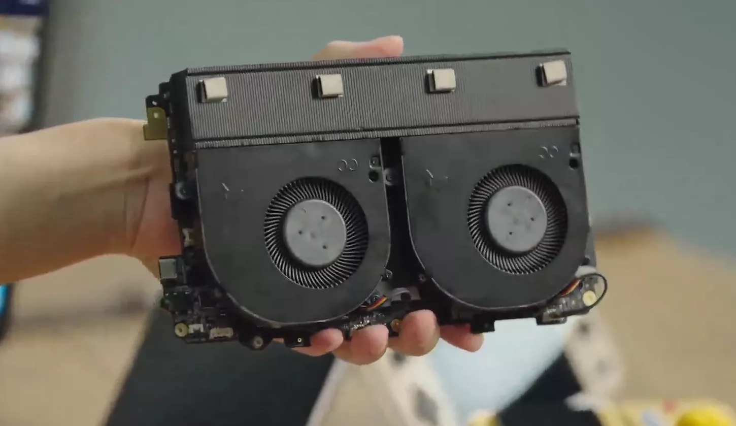 Close-up of a hand holding a laptop's dual cooling fans and heatsink.