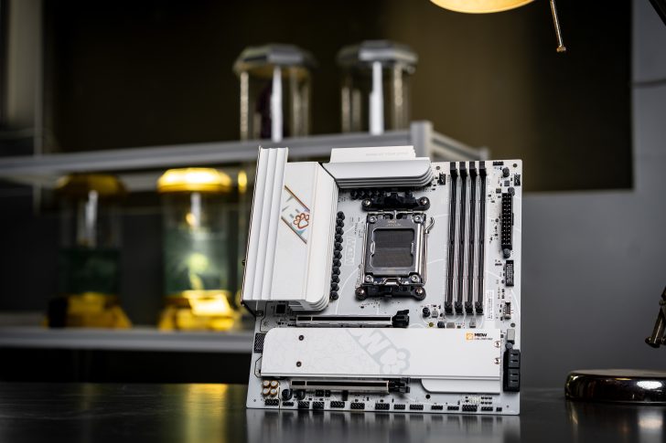A white Meow ROG Crosshair X670E motherboard is displayed on a table with a 'SHINE UP YOUR STYLE' label visible.
