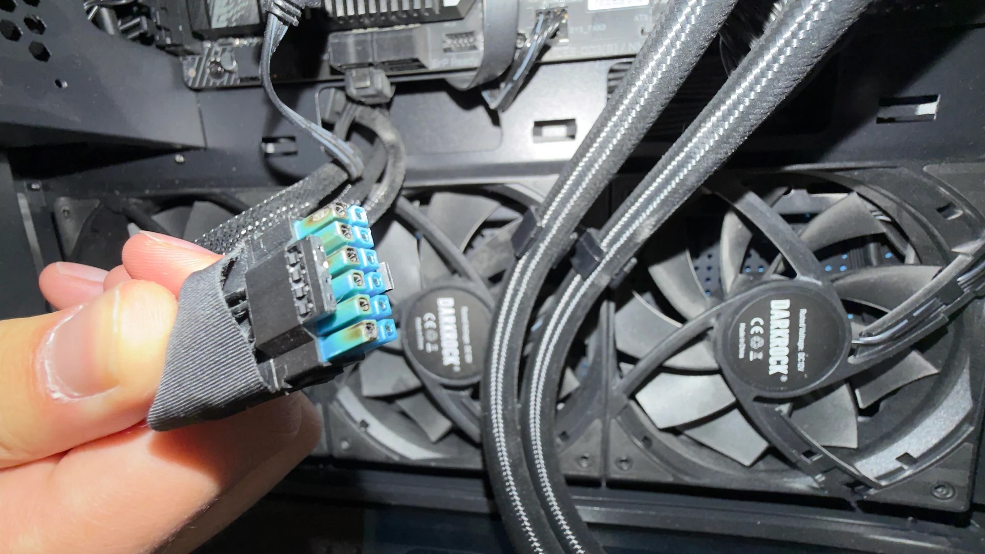 Hand holding unbranded power connector near a be quiet! Dark Rock fan inside a PC.