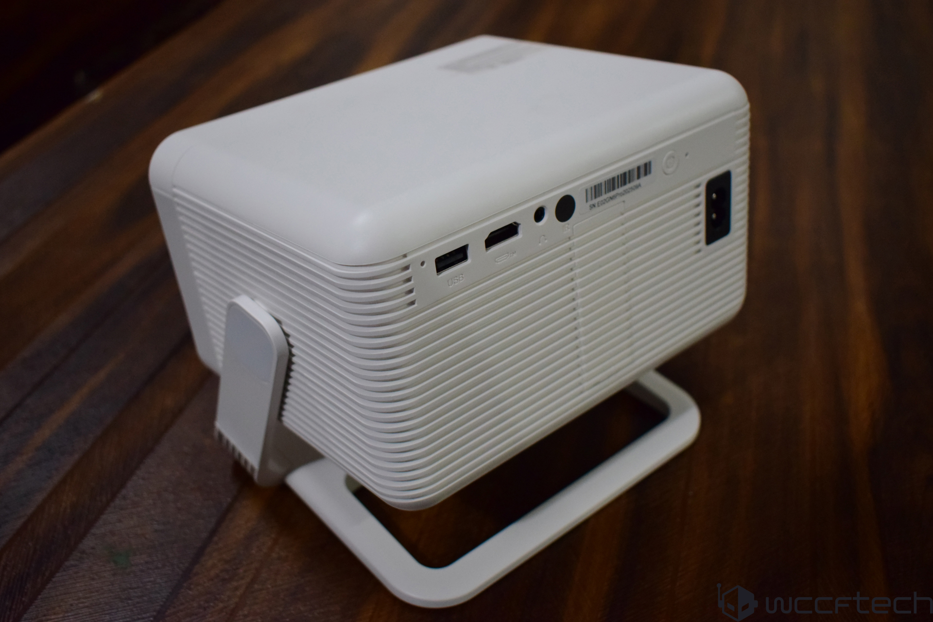 A white project with a stand on a wooden surface, featuring two USB ports, an HDMI port, and an audio jack visible on the side panel.