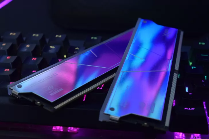 Two ASUS ROG DDR5 memory modules with a reflective metallic finish are placed on a backlit gaming keyboard.