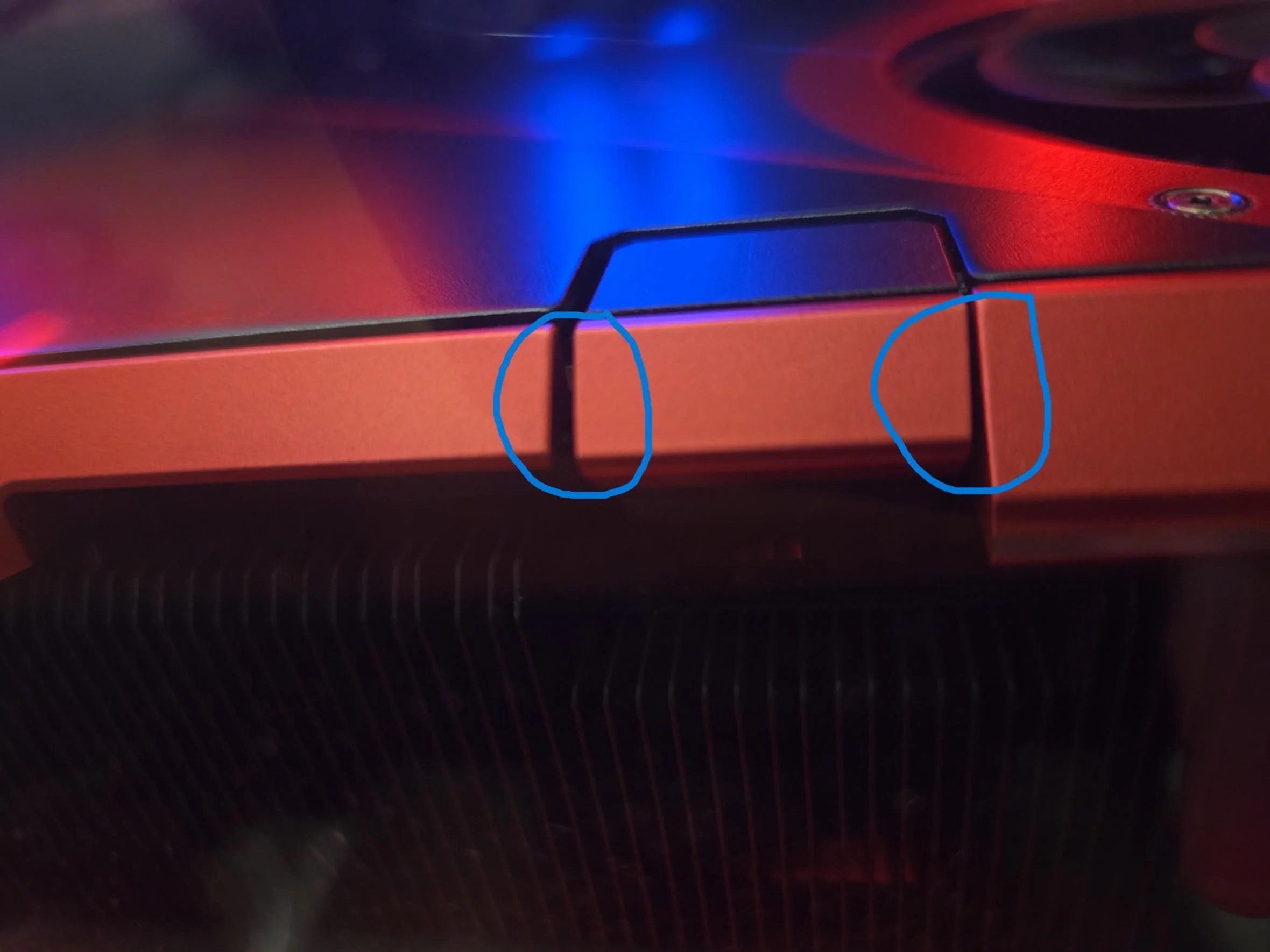 A close-up of a reddish unbranded graphics card with two blue circles highlighting its edges.